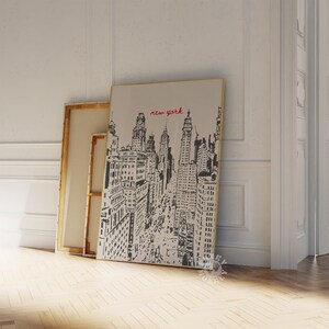 May include: Black and white illustration of a cityscape with the text "new york" in red. The illustration is on a canvas with a gold frame.