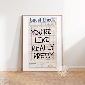 May include: A framed print of a vintage guest check with the text "YOU'RE LIKE REALLY PRETTY" written in black marker. The check has a blue and white design with the words "Guest Check" at the top and "051197" at the bottom.
