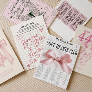 May include: A collection of five rectangular paper prints featuring pink and white designs. Items include a butterfly graphic, three pink tickets to paradise, a library card with handwritten text, a bow illustration, and a newspaper-style print.