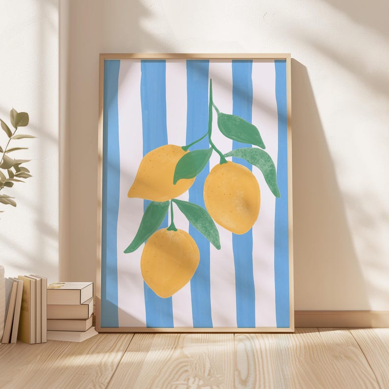 May include: A framed art print featuring a vibrant illustration of lemons on a branch with green leaves. The background has blue and white vertical stripes. The artwork is displayed on a wooden floor.
