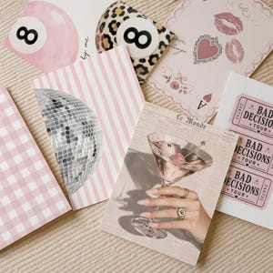 May include: A collection of six rectangular art prints featuring diverse designs including a pink billiard ball, a leopard print eight ball, a playing card with lips, a disco ball on pink stripes, a martini glass, and pink Bad Decisions Tour tickets.