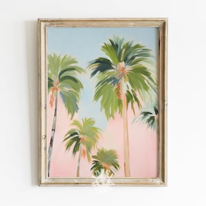 May include: A framed painting of palm trees against a pink and blue sky. The painting is in a light wood frame.
