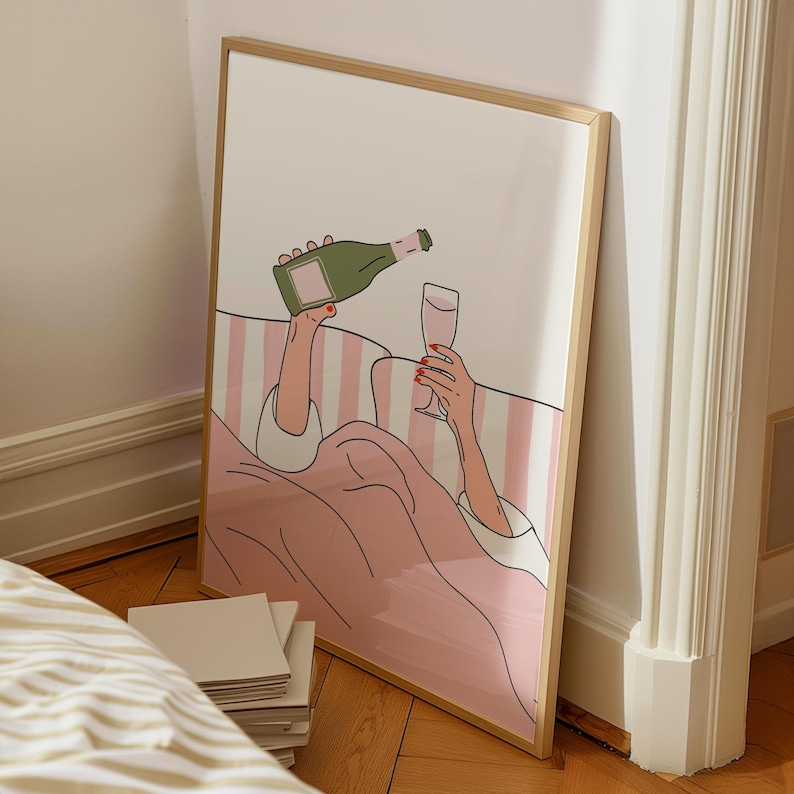 K&ouml;nnte beinhalten: Ein gerahmter Kunstdruck zeigt eine Person, die Champagner einschenkt. Die Illustration zeigt eine gr&uuml;ne Champagnerflasche, ein Glas Champagner und einen rosa-wei&szlig; gestreiften Hintergrund. Das Kunstwerk befindet sich in einem Holzrahmen.