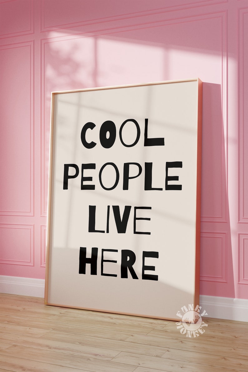 Op de afbeelding: Een ingelijst print met de tekst "COOL PEOPLE LIVE HERE" in zwarte letters op een witte achtergrond.