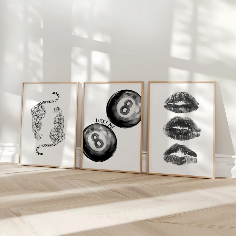 May include: Three black and white framed prints. The left print features two black and white cheetah silhouettes. The middle print features two black and white 8-ball illustrations with the text "Lucky Me". The right print features three black and white lips.