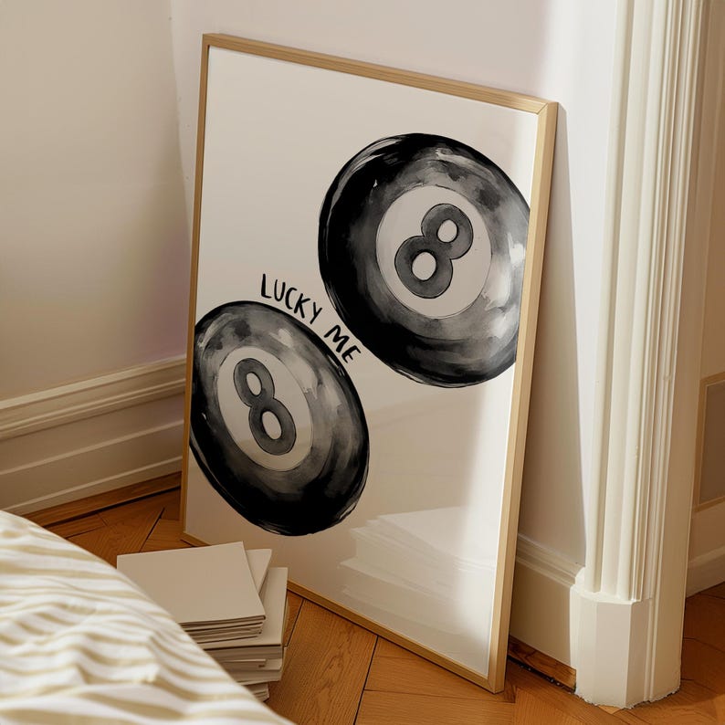May include: A framed print with a white background and two black and white watercolor illustrations of 8-ball pool balls. The text "Lucky Me" is written in black ink above the balls.
