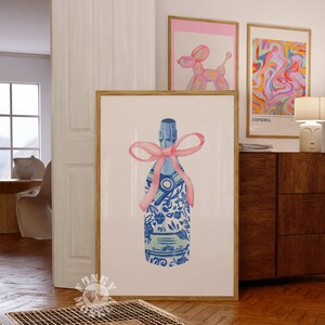 May include: A blue and white patterned champagne bottle with a pink ribbon bow. The bottle is on a white background.