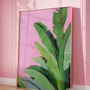 May include: A framed painting of green banana leaves on a pink background. The leaves are painted in a stylized, abstract style.
