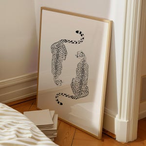 May include: A framed print of two black and white cheetahs, one facing the viewer and the other facing away, on a white background.