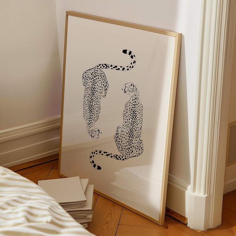 May include: A framed print of two black and white cheetahs, one facing the viewer and the other facing away, on a white background.