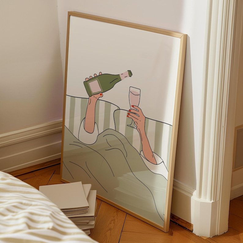 May include: A framed art print depicts a person pouring champagne into a glass while in bed. The illustration features a green champagne bottle, a glass of pink liquid, and a green and white striped background.