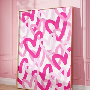 May include: A framed print with a white background and a pattern of pink and fuchsia hearts. The hearts are drawn in a simple, hand-drawn style.