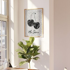 May include: Black and white watercolor print of two cherries with stems and leaves on a background of handwritten text. The text says "Ma Cherie".