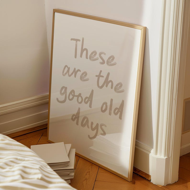 May include: A framed print with the text "These are the good old days" in a light brown color on a white background. The frame is gold.