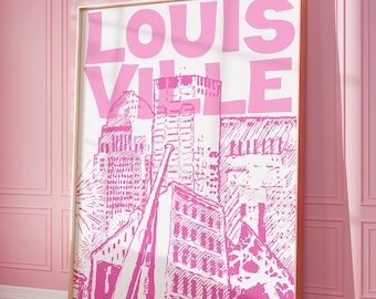 May include: A framed pink and white art print featuring the word "LOUISVILLE" in large capital letters above a stylized illustration of the city's skyline. The artwork is displayed on a pink wall.