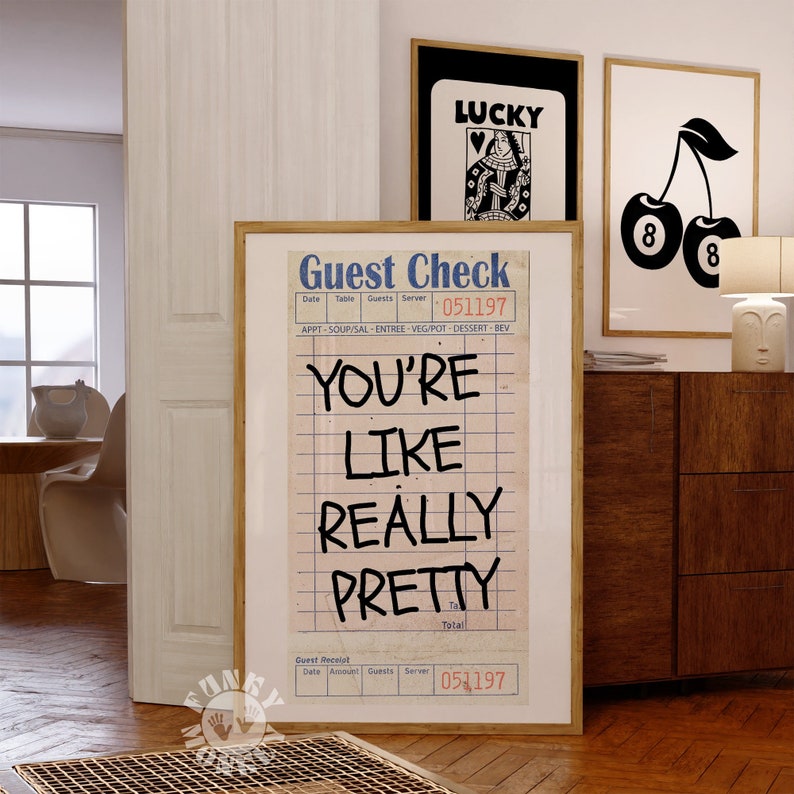 May include: A framed print with a vintage guest check design. The text on the print reads "You're Like Really Pretty" with a handwritten style. The print has a brown wood frame.