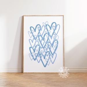 May include: A framed art print featuring a collection of overlapping blue hearts on a white background. The hearts vary in shade, creating depth and visual interest. The artwork is displayed in a wooden frame, adding a touch of warmth.