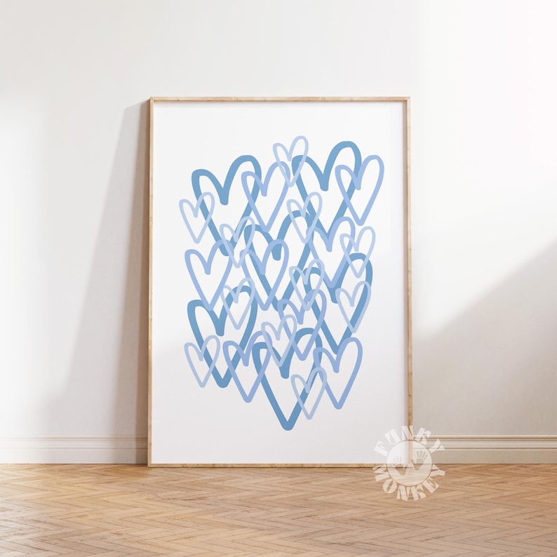 May include: A framed art print featuring a collection of overlapping blue hearts on a white background. The hearts vary in shade, creating depth and visual interest. The artwork is displayed in a wooden frame, adding a touch of warmth.