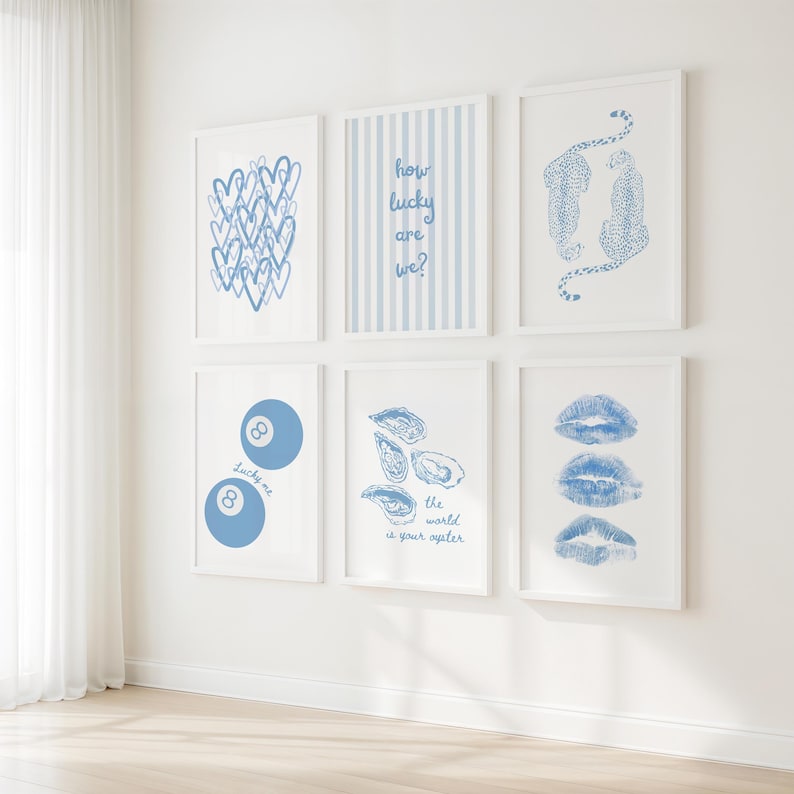 May include: Six framed art prints with white frames and blue designs. The prints feature hearts, stripes, leopards, an 8-ball, oysters, and lip prints. Text includes "how lucky are we?" and "the world is your oyster."