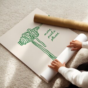 Peut inclure: Une affiche blanche avec une illustration verte de p&acirc;tes et le texte "more pasta please". Une personne roule l'affiche.