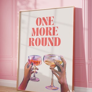 Peut inclure: Une affiche blanche avec le texte "ONE MORE ROUND" en lettres roses. Deux mains tiennent des verres de vin, l'un avec du vin rouge et l'autre avec du vin blanc.