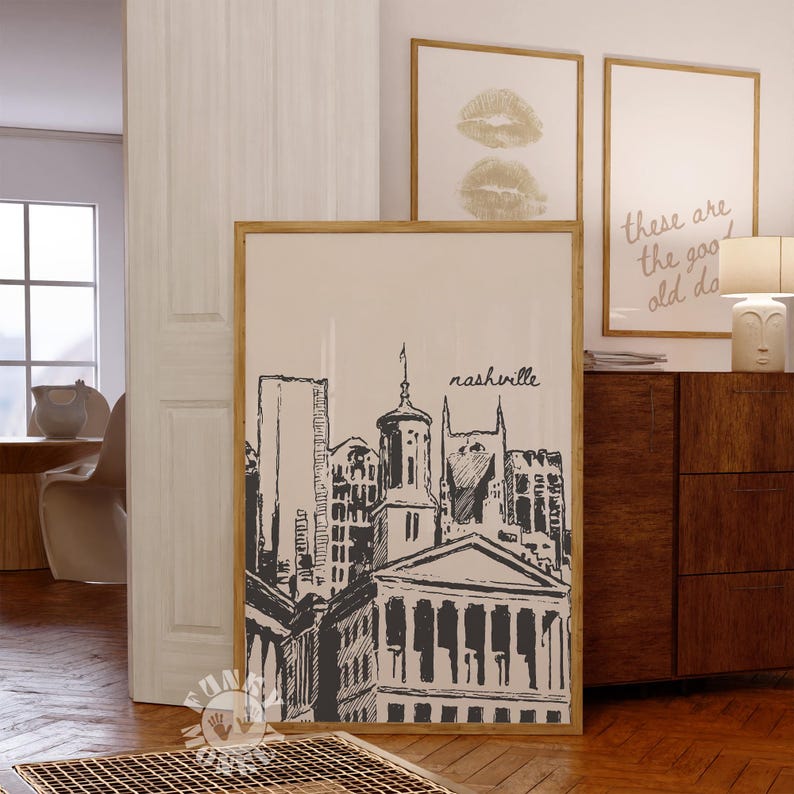 May include: A framed print featuring a black and white illustration of the Nashville skyline. The word "nashville" is written in cursive. The print is in a wooden frame and hangs on a wall.