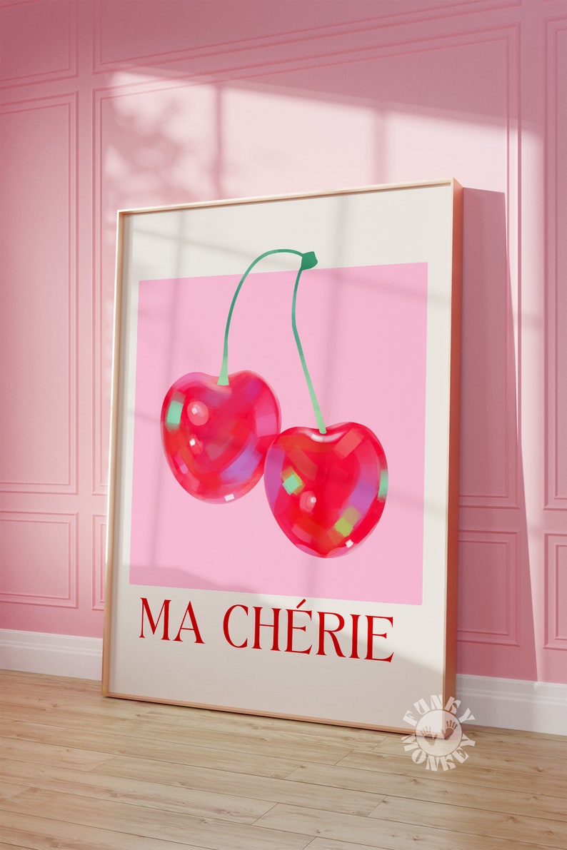 Puede incluir: Una impresi&oacute;n enmarcada con un fondo rosa que presenta dos cerezas rojas con tallos verdes. El texto "MA CHERIE" est&aacute; impreso en rojo en la parte inferior de la impresi&oacute;n.