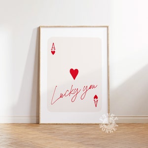 Op de afbeelding: Een printable poster met een rode harten aas speelkaart met de tekst "Lucky you" geschreven in cursief.