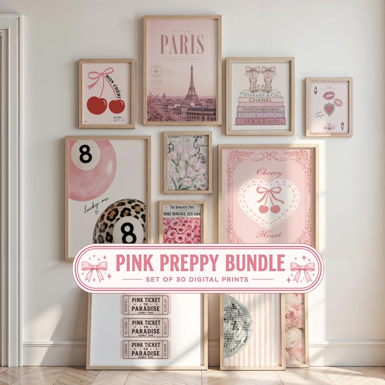 May include: A collection of framed wall art prints featuring pink-themed illustrations including the Eiffel Tower, cherries, high heels, flowers, billiard balls, and ticket stubs. The prints are displayed in light wood frames on a white wall.