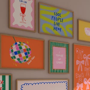 Puede incluir: Una colecci&oacute;n de l&aacute;minas art&iacute;sticas enmarcadas con varios dise&ntilde;os. Una l&aacute;mina presenta una bola de discoteca, otra dice "Cool People Live Here" y otra dice "I Thrive in Chaos". Las l&aacute;minas son de varios colores, incluyendo naranja, rosa y azul.