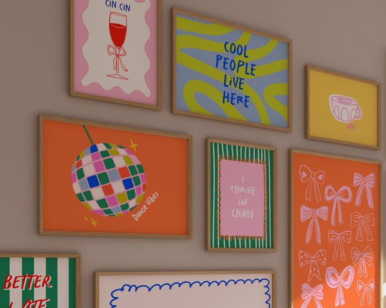 Puede incluir: Una colecci&oacute;n de l&aacute;minas art&iacute;sticas enmarcadas con varios dise&ntilde;os. Una l&aacute;mina presenta una bola de discoteca, otra dice "Cool People Live Here" y otra dice "I Thrive in Chaos". Las l&aacute;minas son de varios colores, incluyendo naranja, rosa y azul.