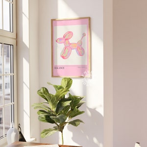 Puede incluir: Una impresi&oacute;n enmarcada con un fondo rosa que presenta un animal de globo de colores con forma de perro. El texto "BALANCE" est&aacute; impreso en negro en la parte inferior de la impresi&oacute;n.
