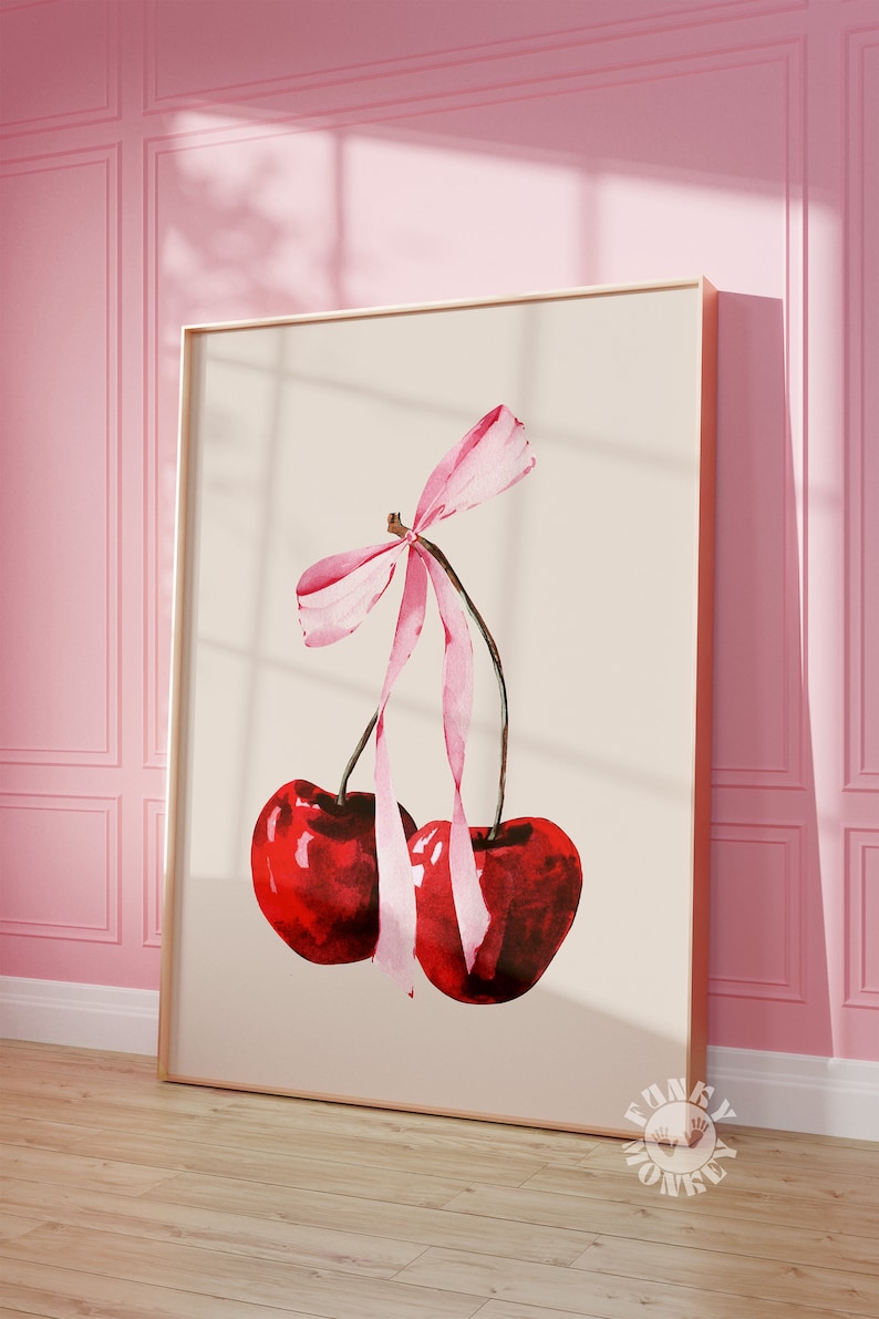May include: A watercolor painting of two red cherries with a pink ribbon tied around the stems. The cherries are on a cream background.
