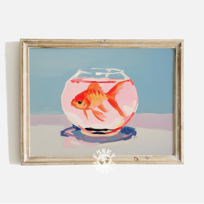 May include: A painting of a goldfish in a round glass bowl. The goldfish is orange and the bowl is filled with pink water. The painting is framed in a light wood frame.