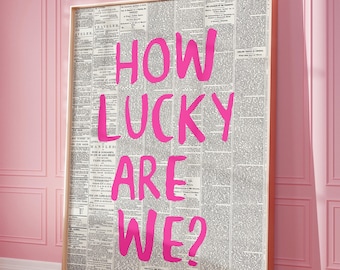 May include: A framed print with a newspaper background and the words "HOW LUCKY ARE WE?" written in pink.