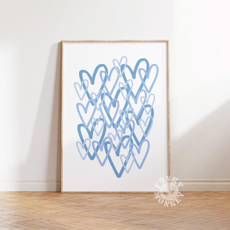 May include: A framed art print featuring a collection of overlapping blue hearts on a white background. The hearts vary in shade, creating depth and visual interest. The artwork is displayed in a wooden frame, adding a touch of warmth.