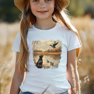 Retro duck hunting tshirt featuring a black lab and mallard ducks by a pond, printed outdoors scene for babies, kids, and adults, perfect for hunting families and dog lovers.