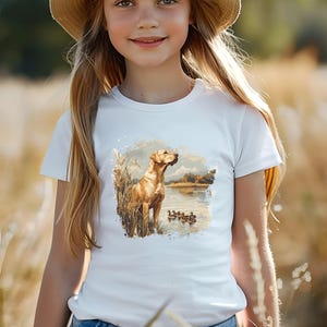 Retro duck hunting t-shirt featuring a yellow lab standing by a pond watching mallard ducks, printed design available in baby, toddler, youth, and adult sizes