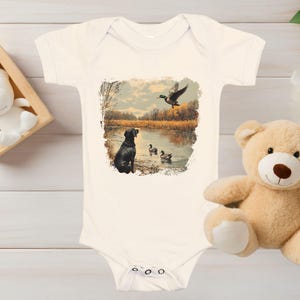 Retro duck hunting baby bodysuit featuring a black lab and mallard ducks by a pond, printed outdoors scene for babies, kids, and adults, perfect for hunting families and dog lovers.