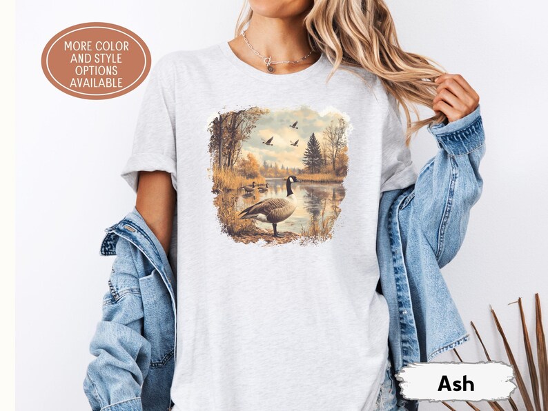 Retro fall scene with a goose by the lake and geese flying overhead, printed on a cozy 90s-style nature crewneck sweatshirt or unisex t-shirt, perfect for bird lovers and wildlife gift giving