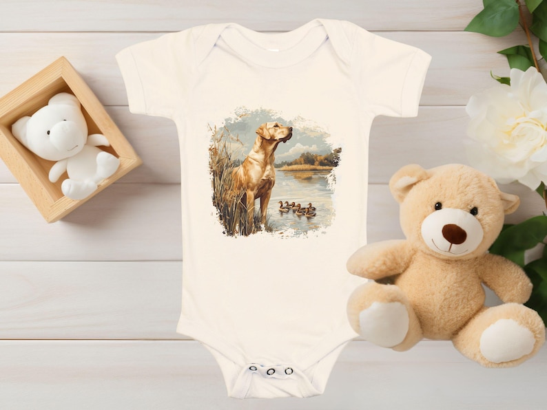 Retro duck hunting t-shirt featuring a yellow lab standing by a pond watching mallard ducks, printed design available in baby, toddler, youth, and adult sizes