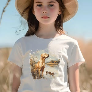 Retro duck hunting t-shirt featuring a yellow lab standing by a pond watching mallard ducks, printed design available in baby, toddler, youth, and adult sizes