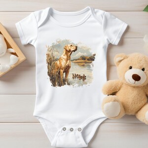 Retro duck hunting t-shirt featuring a yellow lab standing by a pond watching mallard ducks, printed design available in baby, toddler, youth, and adult sizes