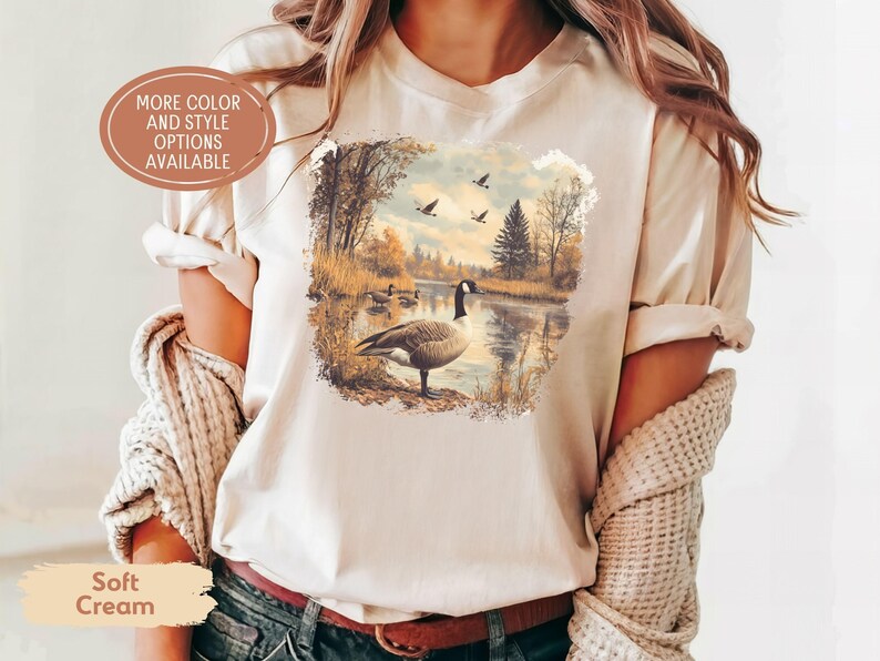 Retro fall scene with a goose by the lake and geese flying overhead, printed on a cozy 90s-style nature crewneck sweatshirt or unisex t-shirt, perfect for bird lovers and wildlife gift giving
