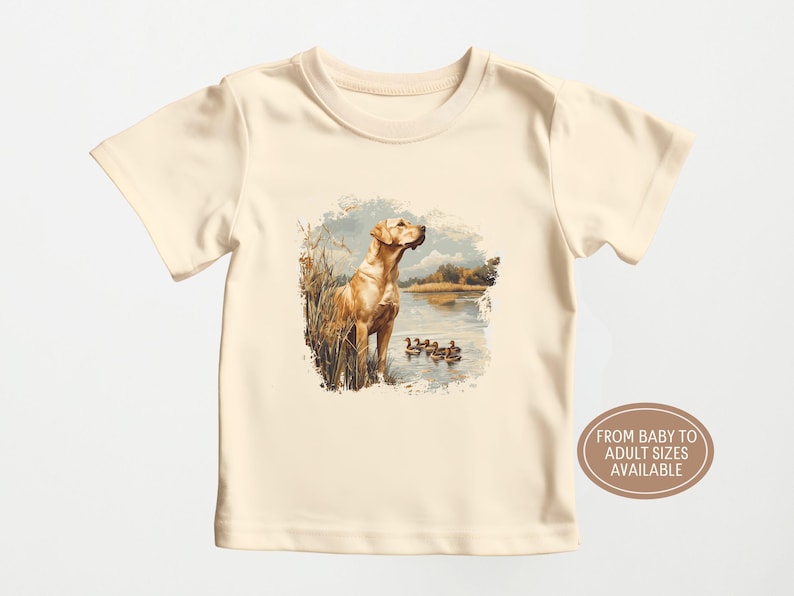 Retro duck hunting t-shirt featuring a yellow lab standing by a pond watching mallard ducks, printed design available in baby, toddler, youth, and adult sizes