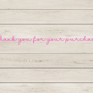 May include: Thank you for your purchase written in pink cursive on a light wood background.