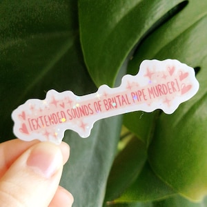 May include: A white sticker with the text "[EXTENDED SOUNDS OF BRUTAL PIPE MURDER]" in pink. The sticker has a glittery, holographic effect and is decorated with pink hearts and stars.