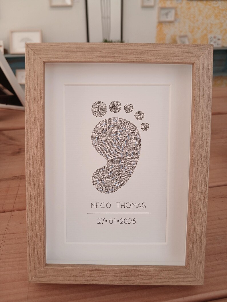 ingelijst babyvoetje gemaakt met handgeschreven woorden. Onder het voetje staat de naam en de geboortedatum van de baby.