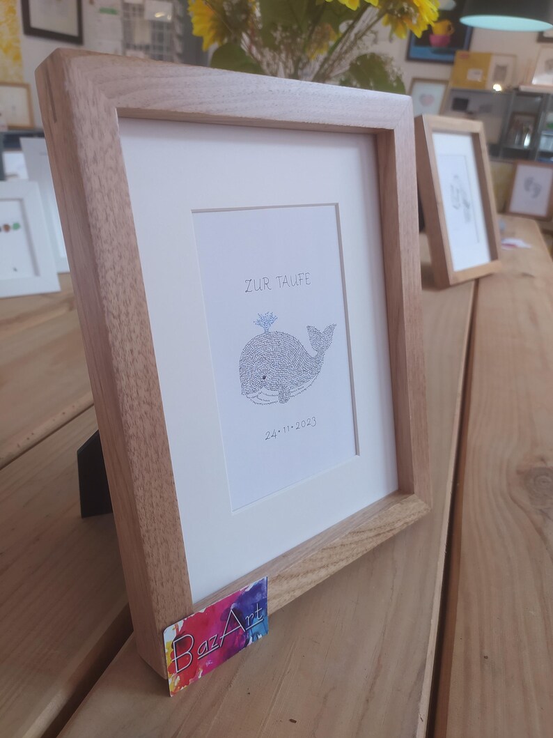 View from the left of a framed image of a baby whale. The complete image consists entirely of handwritten words. In this image the words are hundreds of times the name of the newborn baby.
Under the baby whale is written the date of the baptism.
