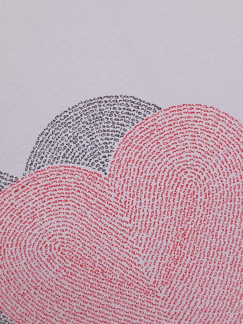 Op de afbeelding: Een wit oppervlak met een hartvormig ontwerp bestaande uit herhaalde tekst. De linkerkant van het hart wordt gevormd door het woord carlos in zwarte inkt, terwijl de rechterkant wordt gevormd door het woord maria in rode inkt, wat een tweekleurig effect geeft.